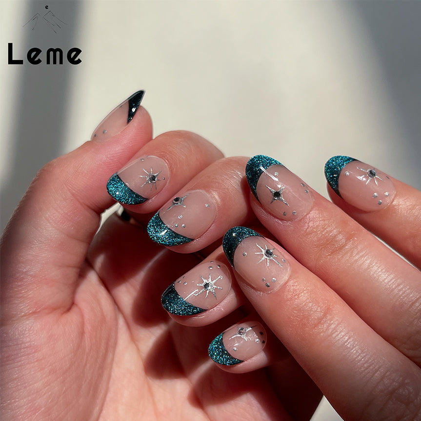 Blue Night is a reusable handmade press-on nails set by Leme. Experience the elegance of our "Blue Night" manicure featuring expertly crafted cat-eye French tips on a subtle nude base. Each short oval-shaped nail is adorned with delicate silver stars and sparkling diamonds, creating a refined and sophisticated look. This design balances understated charm with a touch of luxury, perfect for those seeking a polished and unique style.