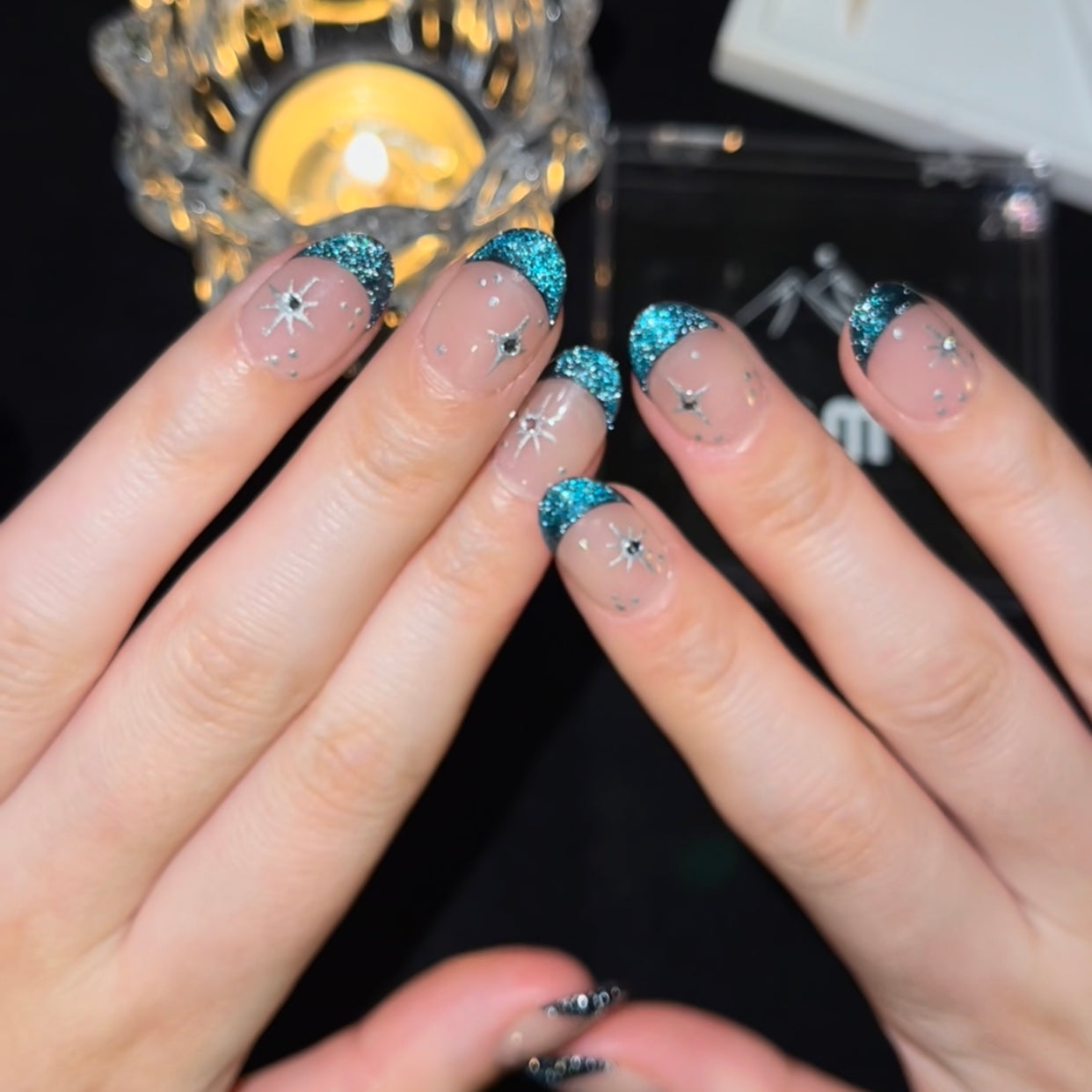 Blue Night is a reusable handmade press-on nails set by Leme. Experience the elegance of our "Blue Night" manicure featuring expertly crafted cat-eye French tips on a subtle nude base. Each short oval-shaped nail is adorned with delicate silver stars and sparkling diamonds, creating a refined and sophisticated look. This design balances understated charm with a touch of luxury, perfect for those seeking a polished and unique style.