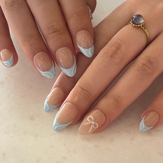 Blue Serenity is a reusable handmade press-on nails set by Leme. These high-quality 3D nails feature a short almond shape with elegant French tips. The delicate baby blue and nude colors create a sophisticated, modern look perfect for any occasion. Designed for durability and style, they offer a flawless finish that enhances your natural nails with expert craftsmanship.