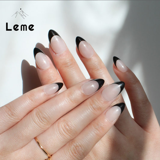 Carina is a reusable handmade press-on nails set by Leme. These sophisticated black French handmade press-on nails feature a chic almond shape, blending modern elegance with timeless style. Meticulously crafted for a precision fit and durability, Leme delivers high-quality results—no appointment needed.