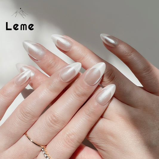 Lady G ‘C is a reusable handmade press-on nails set by Leme. The set offers a refined manicure featuring a sophisticated chrome finish paired with classic white French tips, perfectly crafted in a short almond shape. This elegant design combines classic sophistication with modern subtlety, ideal for those seeking a polished and high-quality look. The precise application ensures durability and a flawless finish, making it suitable for both everyday wear and special occasions.