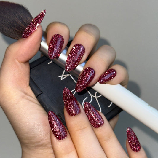 Sweatheart is a reusable handmade press-on nails set by Leme.Elevate your Valentine's Day look with these stunning medium almond-shaped nails featuring a sophisticated raspberry pink glitter base. Each nail is meticulously crafted with premium quality materials to ensure durability and a flawless finish. The intricate firework alike design adds depth and dimension, creating a captivating sparkle that catches the light beautifully. Perfect for the season of love, these nails deliver both elegance and eye-cat