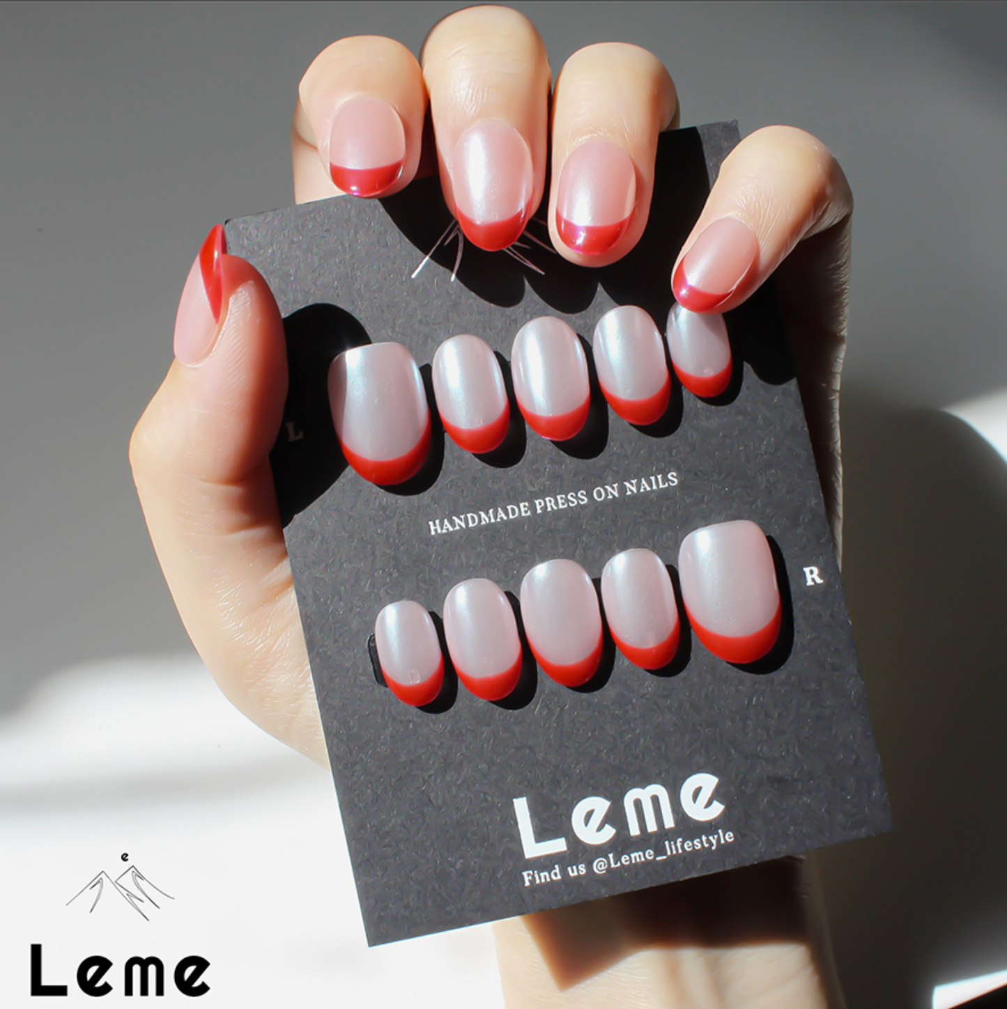 Tiddly Lip is a reusable handmade press-on nails set by Leme. The set offers a sophisticated manicure with its short oval-shaped nails featuring a classic French tip in elegant red and pearl pink tones. Crafted with high-quality chrome finish, these nails provide a sleek, durable look that enhances natural beauty with expert precision. Perfect for a refined, polished appearance.
