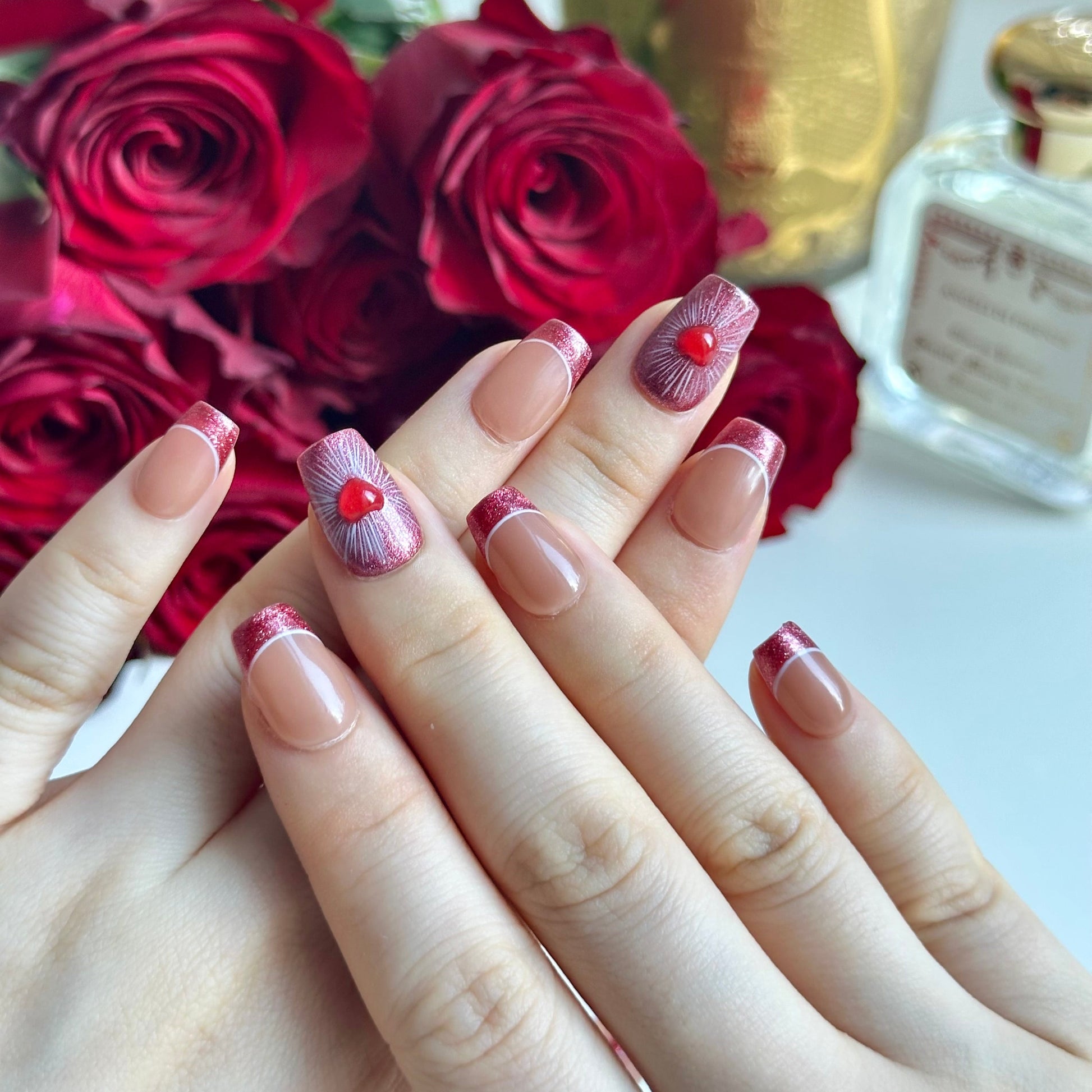 Amour is a reusable handmade press-on nails set by Leme. Elevate your manicure with Amour, our Valentines' special coffin-shaped nails featuring a sophisticated nude base and striking red glitter French tips. Delicate 3D hearts adorned on the middle fingers add a romantic, dimensional touch that catches light beautifully. Meticulously crafted for a flawless finish, these high-quality nails deliver salon-worthy elegance with effortless glamour. Perfect for special occasions or everyday luxury.