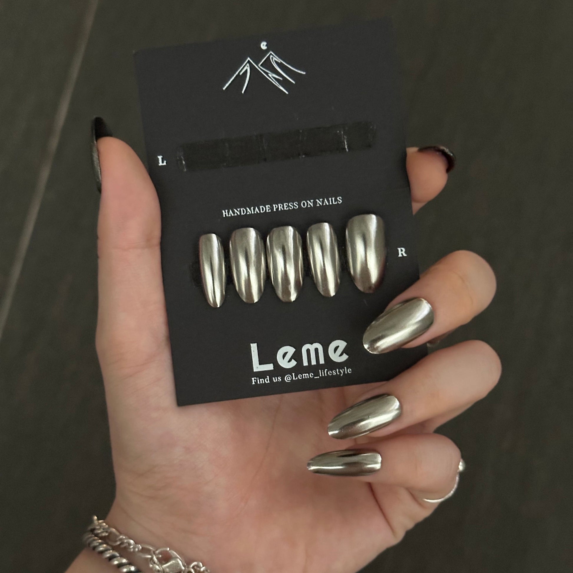 Armor is a reusable handmade press-on nails set by Leme. Introducing this glamorous set, a stunning medium oval piece finished in lustrous silver chrome. Its sleek, polished surface catches the light beautifully, delivering that coveted cool, contemporary aesthetic. Perfect for those who appreciate refined elegance and modern sophistication. The high-quality construction ensures lasting shine and durability, making it an ideal addition to any discerning collection.