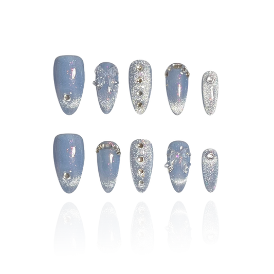 Azure is a reusable handmade press-on nails set by Leme. Elevate your style with the Azure nail design featuring a high-quality blue cat-eye base that delivers a captivating 3D effect. The medium almond shape enhances elegance, while delicate small diamonds and bowtie decorations add refined sparkle and sophistication for a polished, expert finish.
