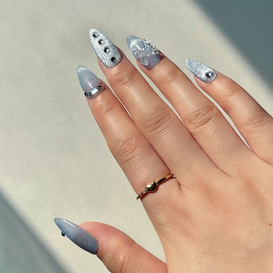 Azure is a reusable handmade press-on nails set by Leme. Elevate your style with the Azure nail design featuring a high-quality blue cat-eye base that delivers a captivating 3D effect. The medium almond shape enhances elegance, while delicate small diamonds and bowtie decorations add refined sparkle and sophistication for a polished, expert finish.