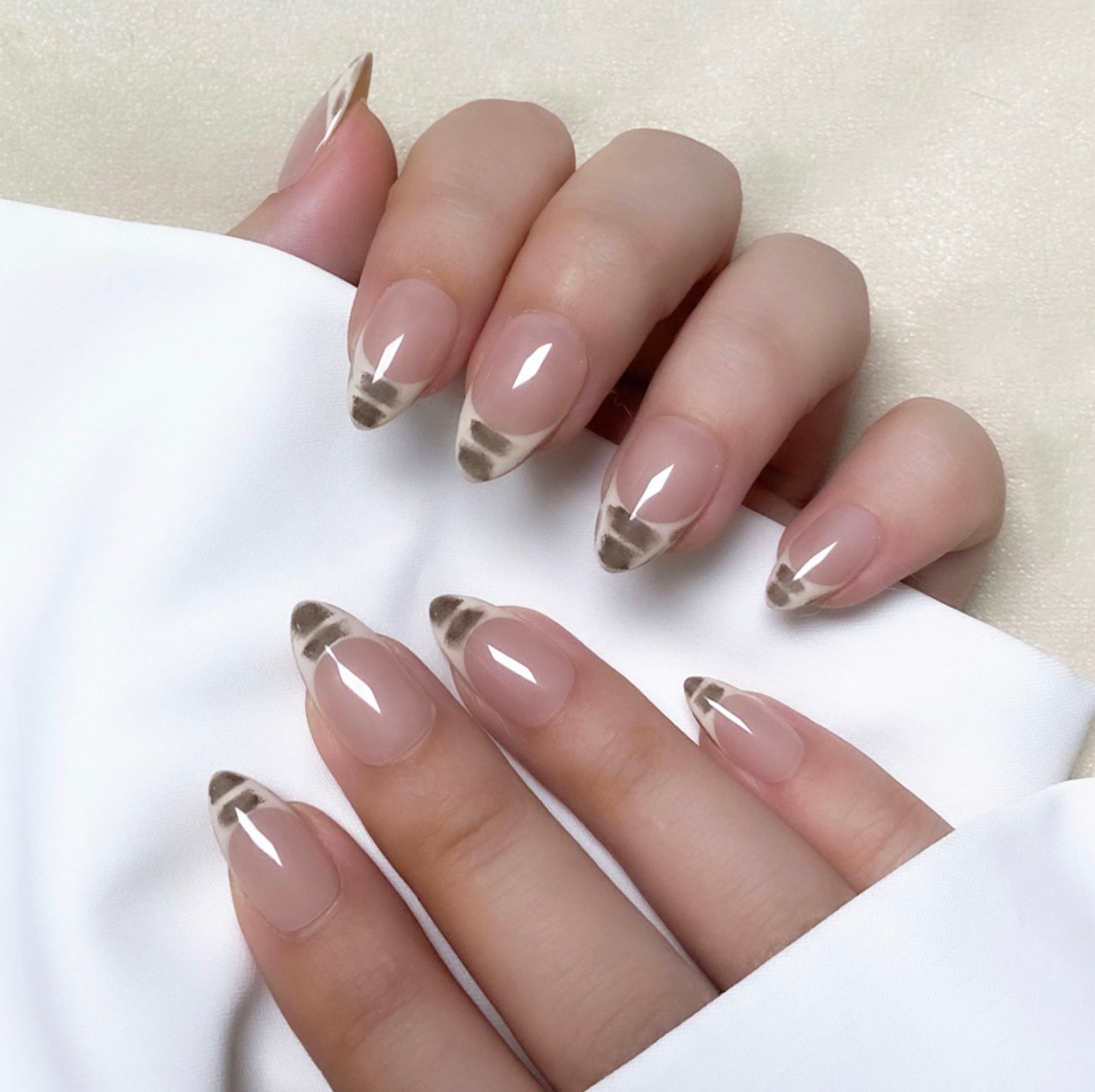 Baby Print is a reusable handmade press-on nails set by Leme. This high-quality nails set features short almond-shaped nails with elegant French tips. The design combines soft nude bases with white and dark brown accents, offering a sophisticated yet fresh look perfect for any occasion.