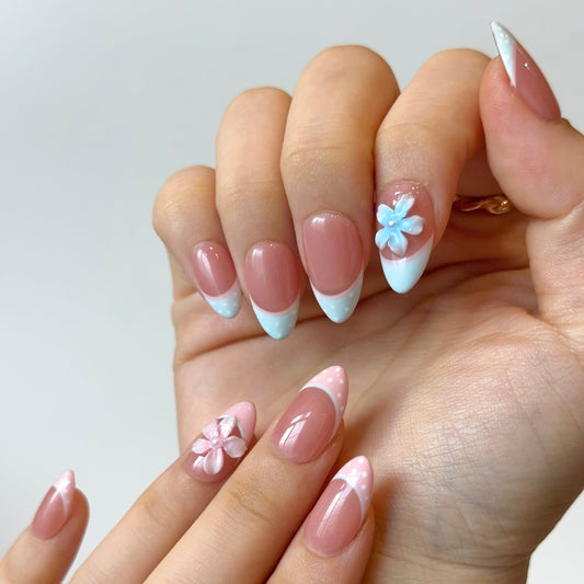 Bambi is a reusable handmade press-on nails set by Leme. The nails feature a soft nude base with delicate pink and blue French tips adorned with playful polka dots. The set showcases 3D handcrafted flowers for added dimension and charm. Available in multiple shapes to suit your preference, these high-quality nails deliver a cute, sophisticated look perfect for any occasion. Simply apply and enjoy salon-worthy results at home.