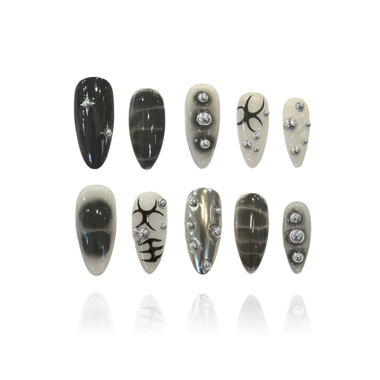 Black Silver Epoch is a reusable handmade press-on nails set by Leme. This set delivers bold, edgy style with a punk rock attitude. Medium almond shape offers a flattering, wearable silhouette that works for everyday wear and statement moments alike. Each set features intricate 3D design work with striking black patterns and silver ball embellishments that catch the light. The dimensional details create depth and texture, elevating these nails beyond flat art—perfect for those who want their manicure to com