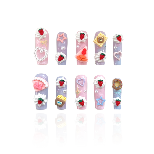 Butter Dream is a reusable handmade press-on nails set by Leme. Experience the Butter Dream from the Candy Cream Collection — high-quality 3D press-on nails featuring a long coffin shape. These light pink and purple nails showcase charming designs inspired by cakes, teddy bears, and desserts, adding a playful yet sophisticated touch to your look. Durable and easy to apply, they offer a flawless finish perfect for elevating any style with expert precision.