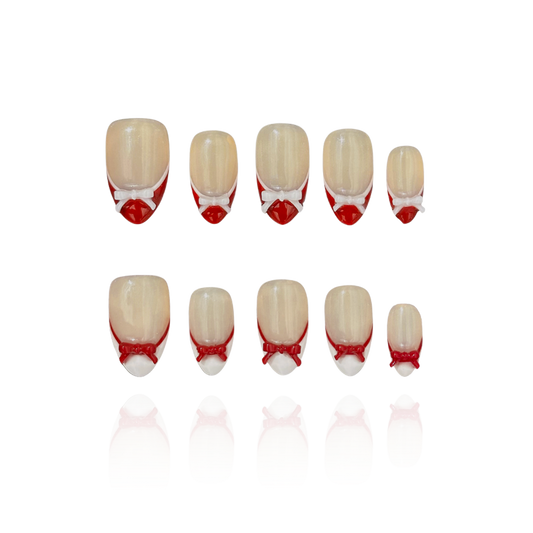 Candy Bow is a reusable handmade press-on nails set by Leme. Elevate your manicure with Candy Bow, a sophisticated press-on nail set featuring a nude base and multiple refined shapes available. Each tip showcases hand-applied French detailing in crisp red and white, crowned with delicate red and white 3D bow accents for a polished, editorial finish. Crafted from premium materials, these nails deliver salon-quality results with effortless application. Perfect for adding a touch of refined elegance to any occ