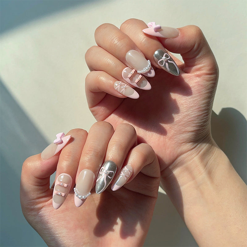 Charlotte is a reusable handmade press-on nails set by Leme. Elevate your nail game with Charlotte, a delicate ballet-inspired press-on set that captures timeless elegance. This medium almond design features a soft nude base with chic pink French tips, accented by two shimmering chrome nails for a modern touch. Tiny pearls delicately adorn select nails, while adorable pink bows grace each thumb—a whimsical detail that brings the entire look together. Perfect for those who love a refined, romantic aesthetic 