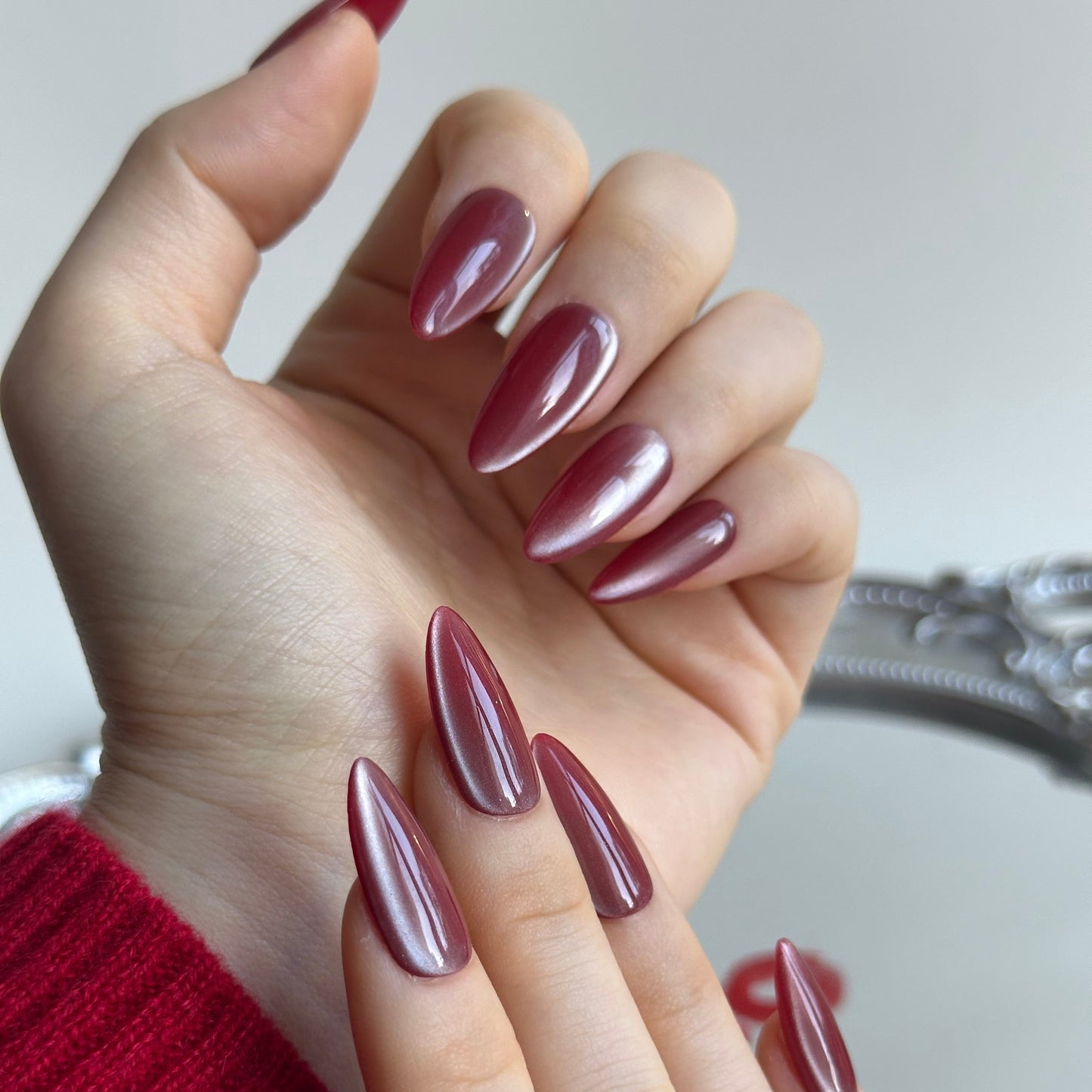 Cherry Bite is a reusable handmade press-on nails set by Leme. Elevate your Valentine's Day look with Cherry Bite, our expertly crafted medium almond-shaped press-on nails. Each nail features a gentle brown-red cat-eye finish enhanced with luxurious silver shimmer, creating a captivating depth that catches light beautifully. The almond silhouette flatters any hand shape while maintaining a sophisticated edge. Designed for flawless application and lasting wear, these high-quality nails deliver salon-level re