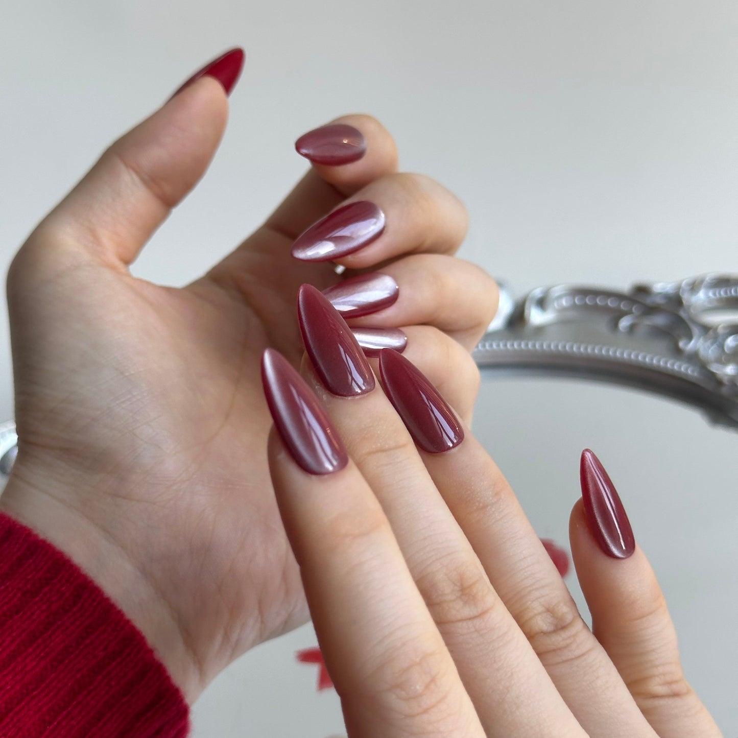 Cherry Bite is a reusable handmade press-on nails set by Leme. Elevate your Valentine's Day look with Cherry Bite, our expertly crafted medium almond-shaped press-on nails. Each nail features a gentle brown-red cat-eye finish enhanced with luxurious silver shimmer, creating a captivating depth that catches light beautifully. The almond silhouette flatters any hand shape while maintaining a sophisticated edge. Designed for flawless application and lasting wear, these high-quality nails deliver salon-level re