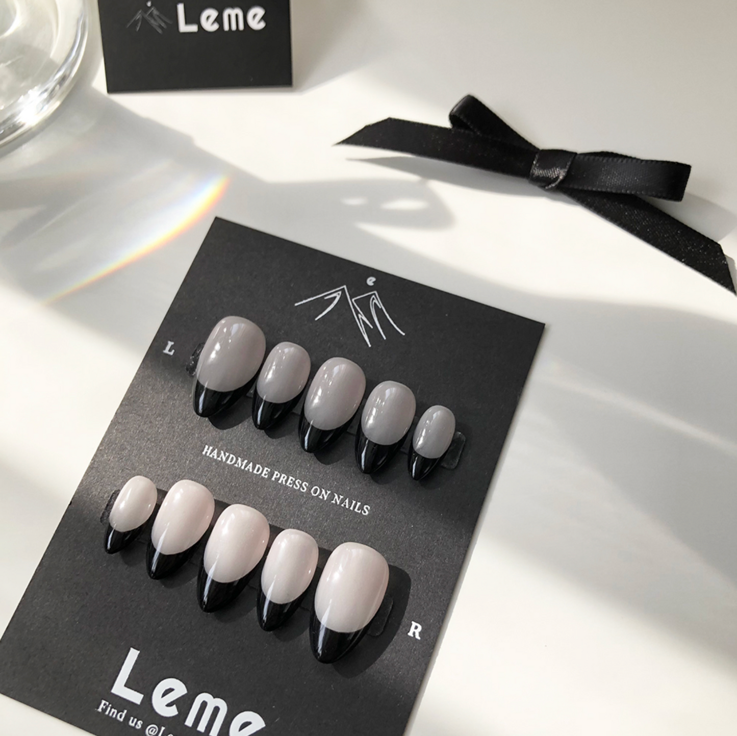 Carina is a reusable handmade press-on nails set by Leme. These sophisticated black French handmade press-on nails feature a chic almond shape, blending modern elegance with timeless style. Meticulously crafted for a precision fit and durability, Leme delivers high-quality results—no appointment needed.
