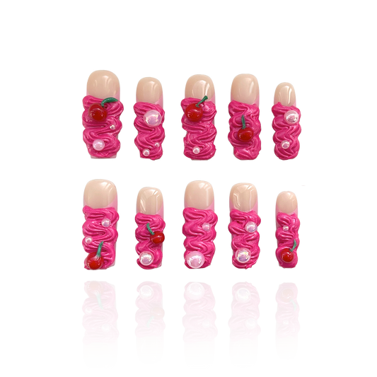 Cherry Bomb is a reusable handmade press-on nails set by Leme. Elevate your manicure with the Cherry Bomb from our Candy Cream Collection. These long square-shaped, 3D press-on nails feature a creamy texture in vibrant hot pink, adorned with delicate cherries and pearls. Handmade with high-quality materials, they offer a reusable and durable option for a flawless, expert finish every time.