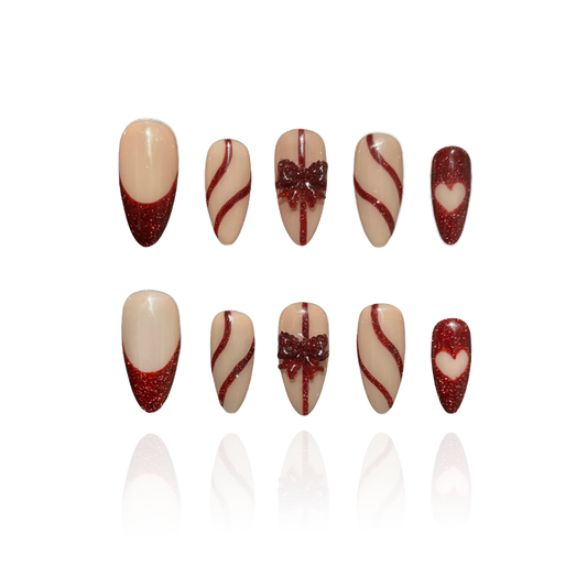 Gift Box is a reusable handmade press-on nails set by Leme. Elevate your nail game with this sophisticated press-on set featuring a medium almond shape and timeless French tip design. The nude base provides a versatile canvas, while glitter red accents add glamorous dimension. Delicate 3D bows adorning the middle fingers create a refined focal point that balances elegance with playful detail. Crafted from premium materials for a salon-quality finish, this set delivers professional results with effortless ap