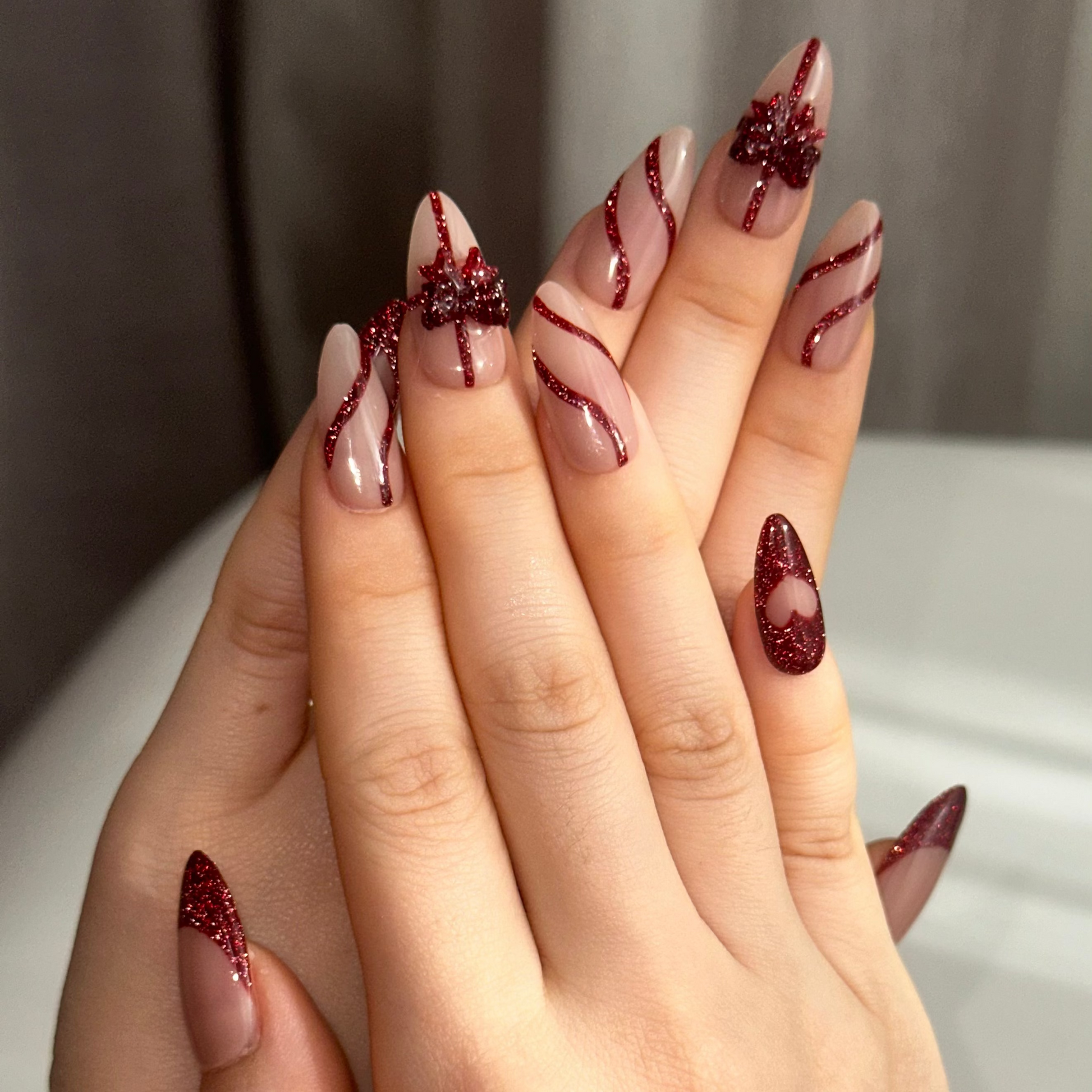 Gift Box is a reusable handmade press-on nails set by Leme. Elevate your nail game with this sophisticated press-on set featuring a medium almond shape and timeless French tip design. The nude base provides a versatile canvas, while glitter red accents add glamorous dimension. Delicate 3D bows adorning the middle fingers create a refined focal point that balances elegance with playful detail. Crafted from premium materials for a salon-quality finish, this set delivers professional results with effortless ap