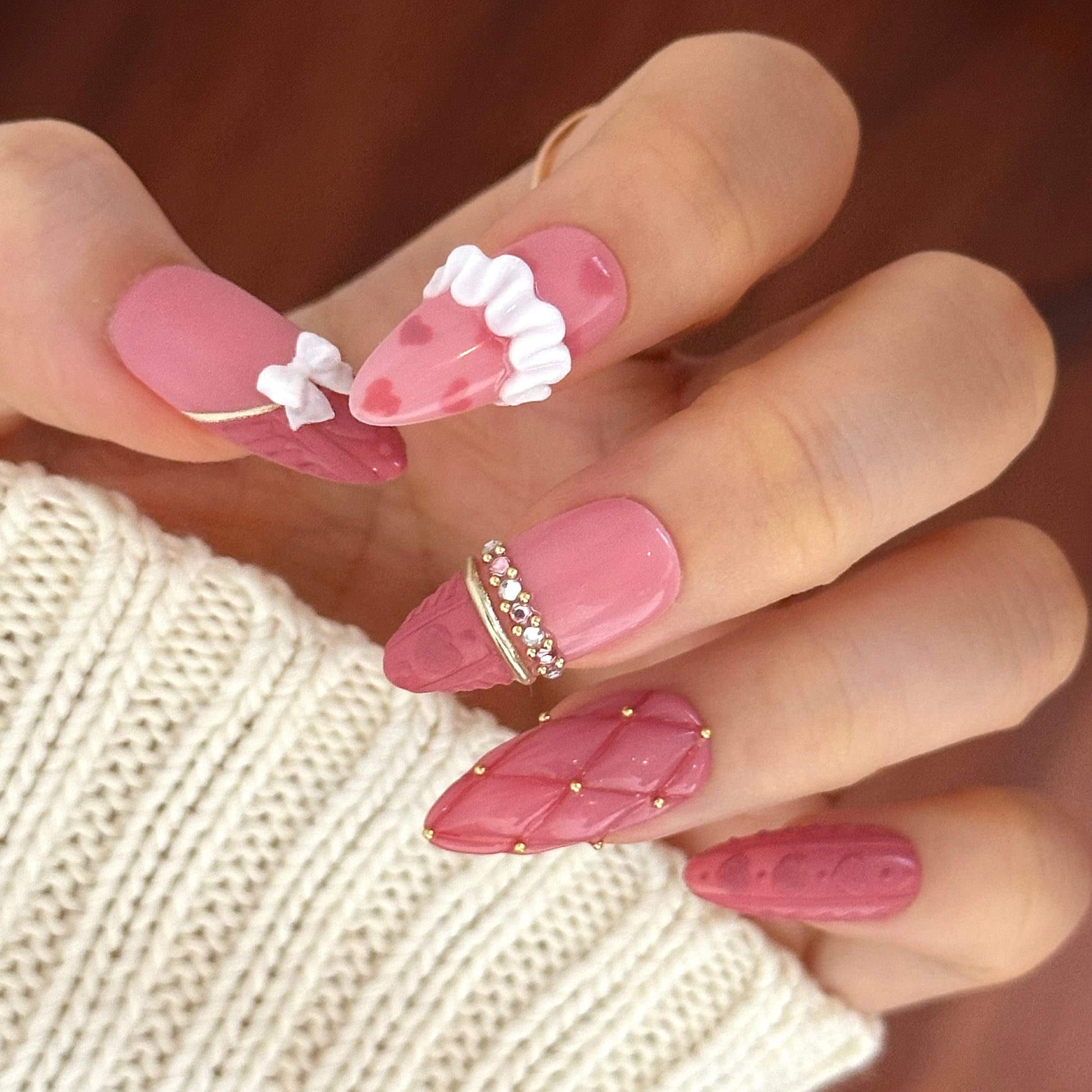 Gold Promise is a reusable handmade press-on nails set by Leme. Discover Gold Promise, an exquisite nail collection that captures timeless elegance through meticulous craftsmanship. These medium almond-shaped nails feature a romantic pink base paired with classic French tips adorned in a soft sweater texture for subtle sophistication. The design showcases premium 3D embellishments complemented by strategically placed gems and gold chrome accents that form delicate ring-like details across the nail surface. 
