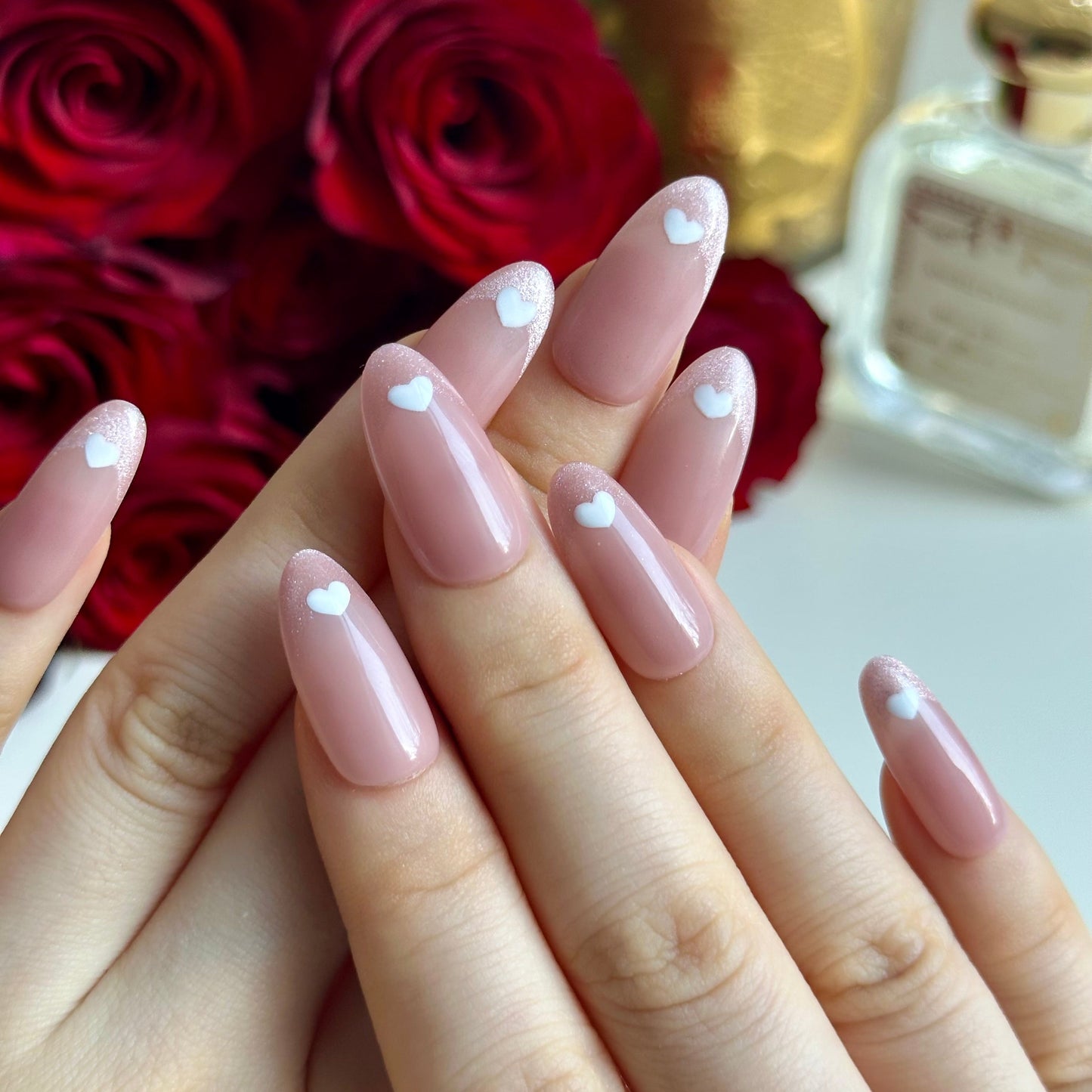 Love Letter is a reusable handmade press-on nails set by Leme. Elevate your manicure with Love Letter, a sophisticated medium oval nail design that captures timeless elegance. These cat-eye French tips feature a delicate pink nude base adorned with hand-drawn hearts, blending classic refinement with romantic detail. The expertly crafted medium oval shape flatters any hand, while the precise cat-eye finish adds dimension and depth. Whether you're planning a romantic evening or simply embracing the season of 