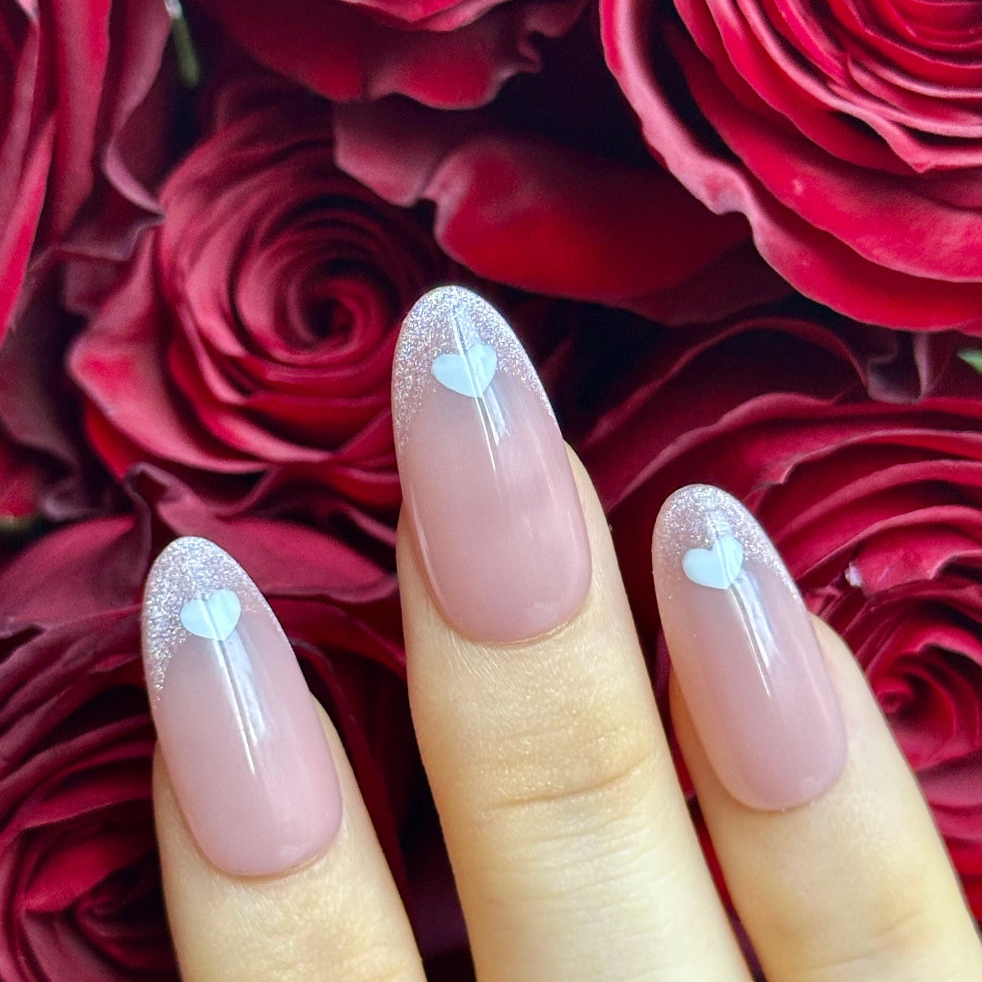 Love Letter is a reusable handmade press-on nails set by Leme. Elevate your manicure with Love Letter, a sophisticated medium oval nail design that captures timeless elegance. These cat-eye French tips feature a delicate pink nude base adorned with hand-drawn hearts, blending classic refinement with romantic detail. The expertly crafted medium oval shape flatters any hand, while the precise cat-eye finish adds dimension and depth. Whether you're planning a romantic evening or simply embracing the season of 