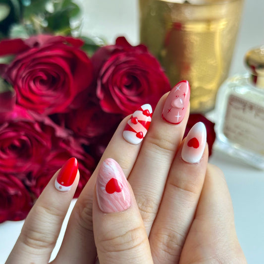 Rosy Ocean is a reusable handmade press-on nails set by Leme. Rosy Ocean captures the essence of romance with its expertly crafted design. Featuring hand-drawn rose paired with delicate 3D hearts, this short almond-shaped nail set delivers a sophisticated yet playful aesthetic. The Valentine's collection showcases a harmonious blend of white, pink, and red tones that complement any complexion. Each nail displays meticulous attention to detail, making this a standout choice for those seeking distinctive, hig