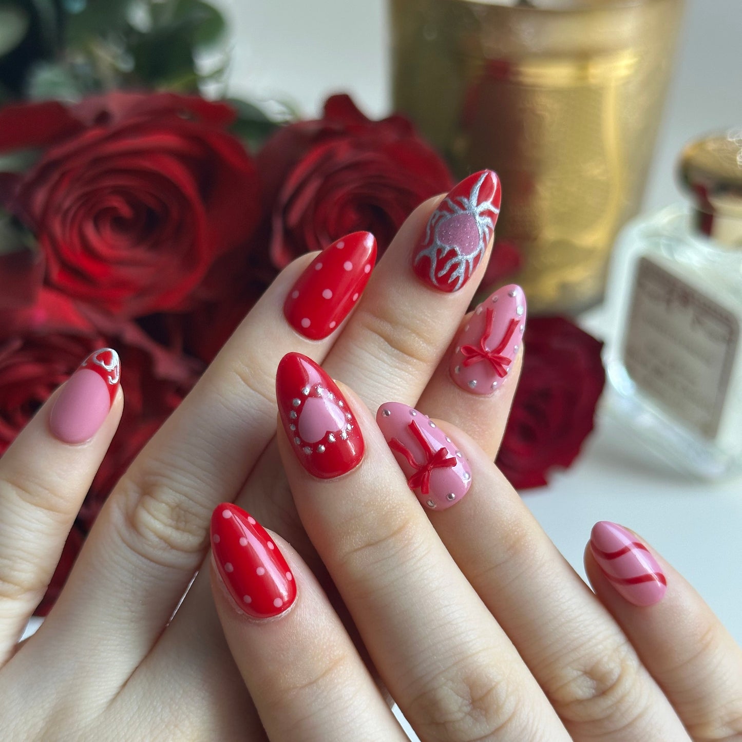 Silver Kisses is a reusable handmade press-on nails set by Leme. Elevate your Valentine's Day look with Silver Kisses, a high-quality short almond nail design from our exclusive Valentine's collection. This striking design features lustrous silver chrome accents paired with dimensional 3D cherry details, creating an eye-catching contrast. The bold palette of hot red and pink celebrates uninhibited romance and passionate self-expression. A glittering heart adorns the middle finger as the statement focal poin