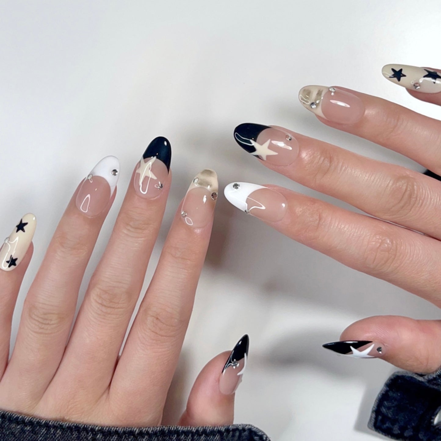 Starry Chic is a reusable handmade press-on nails set by Leme. Elevate your nails with the Starry Chic design, featuring an oval shape and a nude base that highlights cute black and white French tips. Accented with creamy yellow hues, delicate stars, and small diamonds, this high-quality press-on nails set offers a sophisticated yet playful look perfect for any occasion.