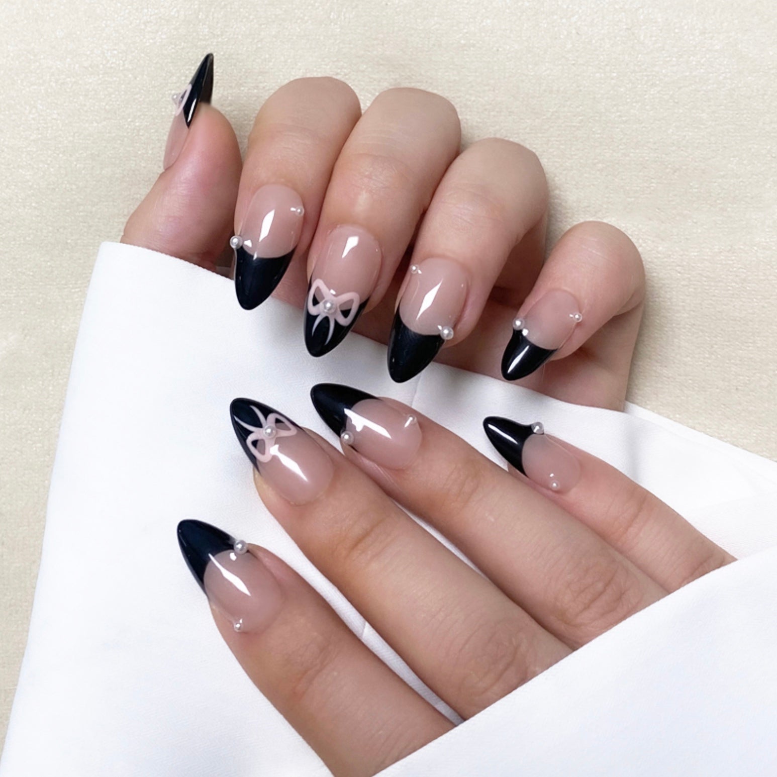 Tie Me is a reusable handmade press-on nails set by Leme. Elevate your nail style with "Tie Me," featuring expertly crafted almond-shaped nails and intricate 3D designs. These high-quality nails showcase a chic nude base accented by elegant black French tips and a delicate pink bow tie design, combining sophistication with a playful touch. Perfect for those seeking a refined yet unique manicure look.