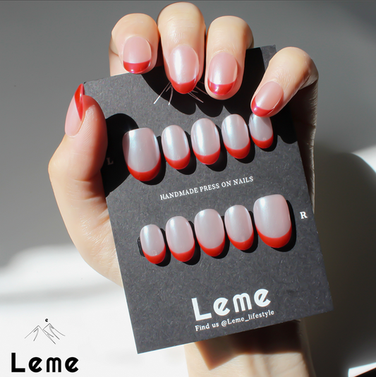 Tiddly Lip is a reusable handmade press-on nails set by Leme. The set offers a sophisticated manicure with its short oval-shaped nails featuring a classic French tip in elegant red and pearl pink tones. Crafted with high-quality chrome finish, these nails provide a sleek, durable look that enhances natural beauty with expert precision. Perfect for a refined, polished appearance.