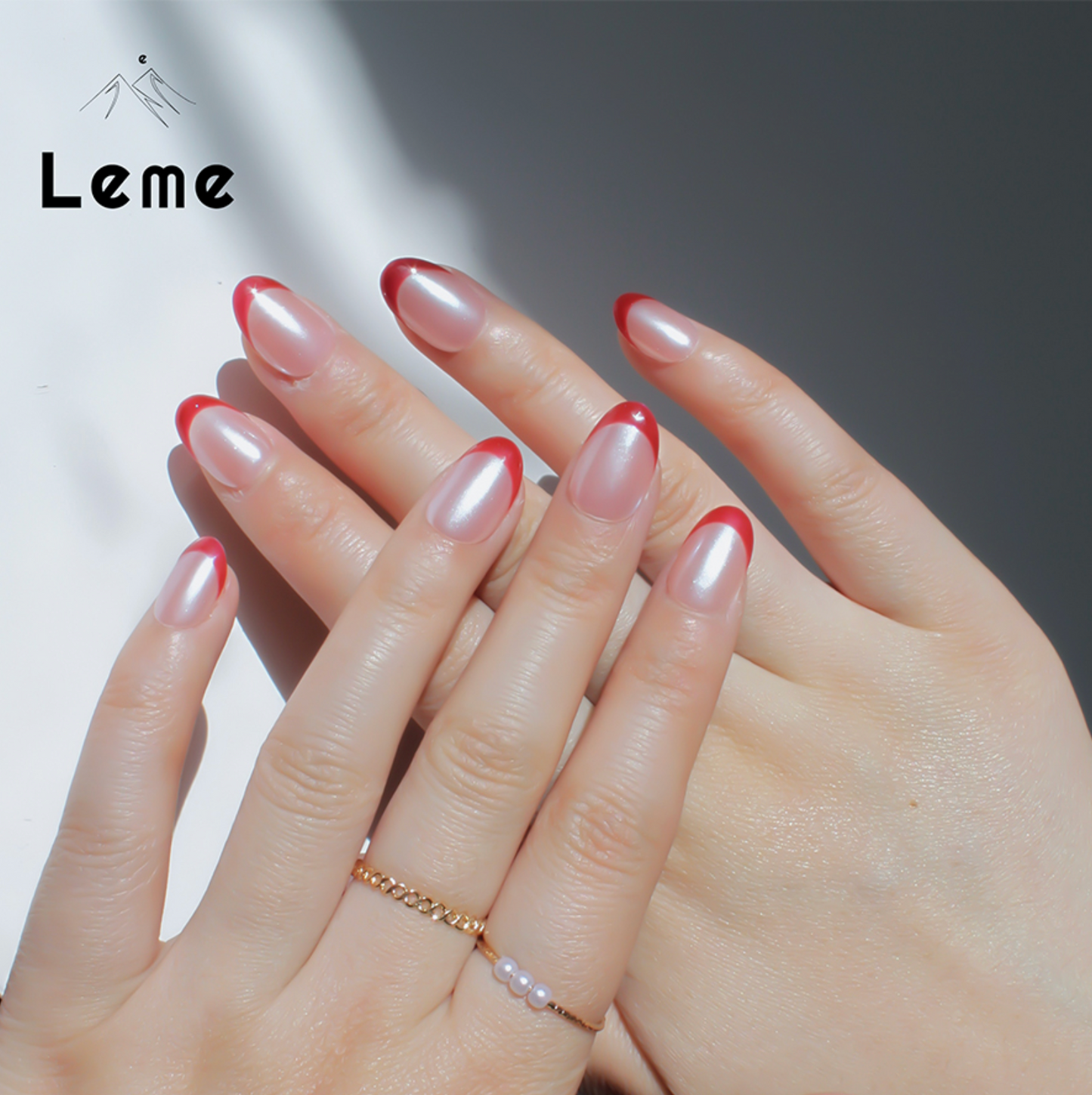 Tiddly Lip is a reusable handmade press-on nails set by Leme. The set offers a sophisticated manicure with its short oval-shaped nails featuring a classic French tip in elegant red and pearl pink tones. Crafted with high-quality chrome finish, these nails provide a sleek, durable look that enhances natural beauty with expert precision. Perfect for a refined, polished appearance.