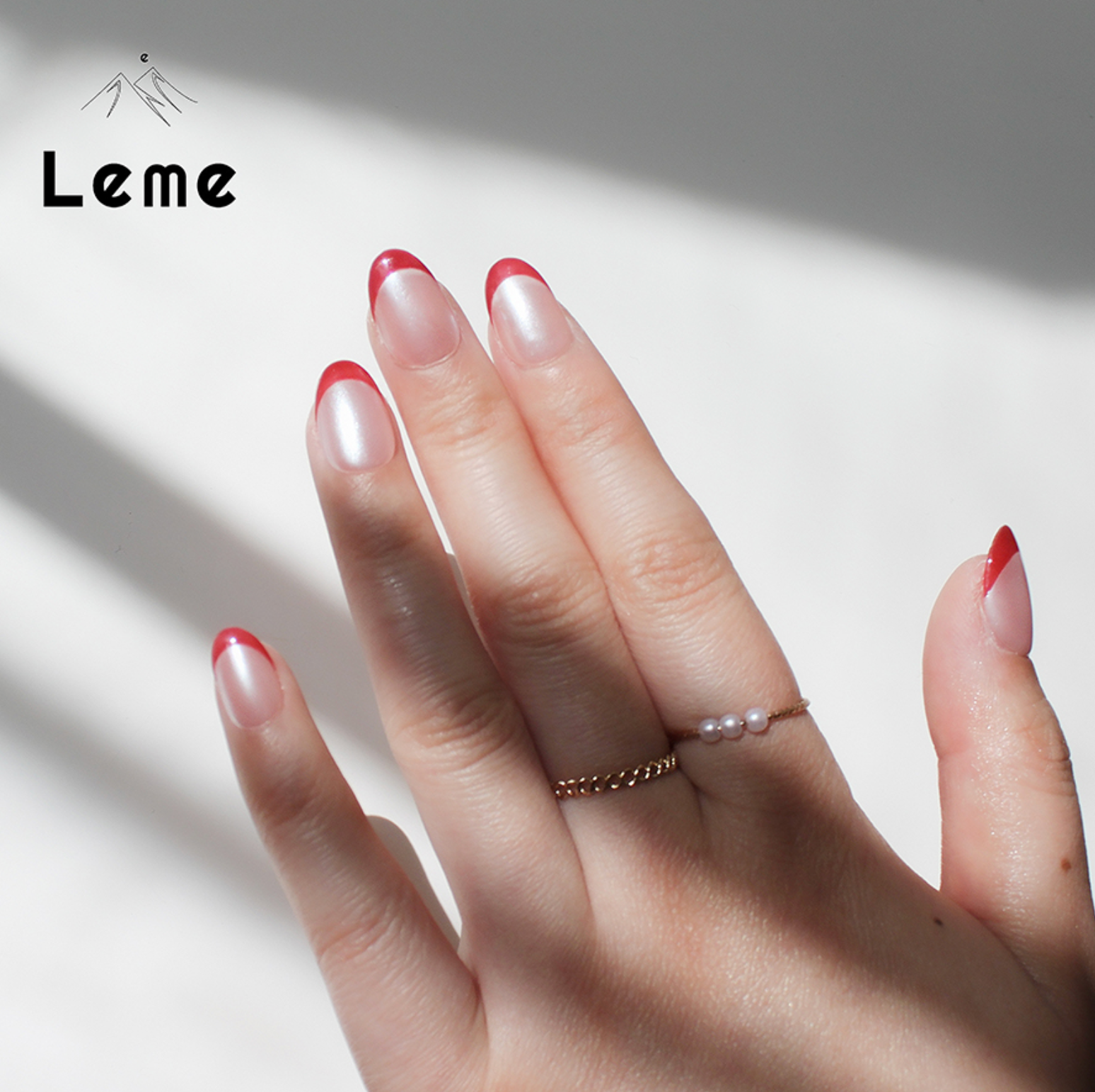 Tiddly Lip is a reusable handmade press-on nails set by Leme. The set offers a sophisticated manicure with its short oval-shaped nails featuring a classic French tip in elegant red and pearl pink tones. Crafted with high-quality chrome finish, these nails provide a sleek, durable look that enhances natural beauty with expert precision. Perfect for a refined, polished appearance.