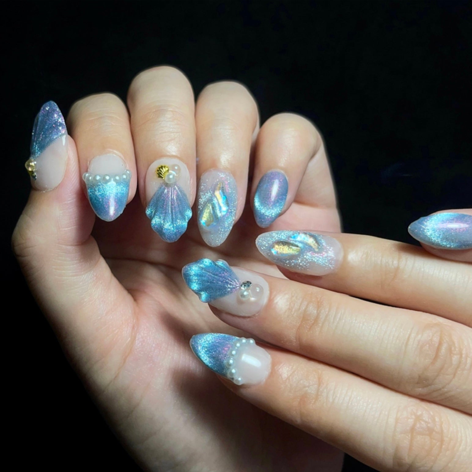 Treasure Beneath is a reusable handmade press-on nails set by Leme. Experience the elegance of "Treasure Beneath" nails, featuring expertly crafted short almond-shaped tips with a sophisticated blue cat-eye effect. These high-quality 3D nails showcase delicate water-inspired designs on a pristine white base, accented with lustrous pearls for a refined, dimensional look. Perfect for those seeking a subtle yet striking manicure that combines artistry with durability.