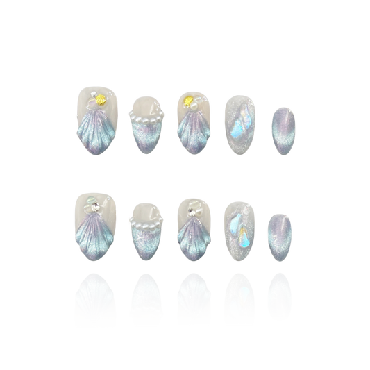 Treasure Beneath is a reusable handmade press-on nails set by Leme. Experience the elegance of "Treasure Beneath" nails, featuring expertly crafted short almond-shaped tips with a sophisticated blue cat-eye effect. These high-quality 3D nails showcase delicate water-inspired designs on a pristine white base, accented with lustrous pearls for a refined, dimensional look. Perfect for those seeking a subtle yet striking manicure that combines artistry with durability.